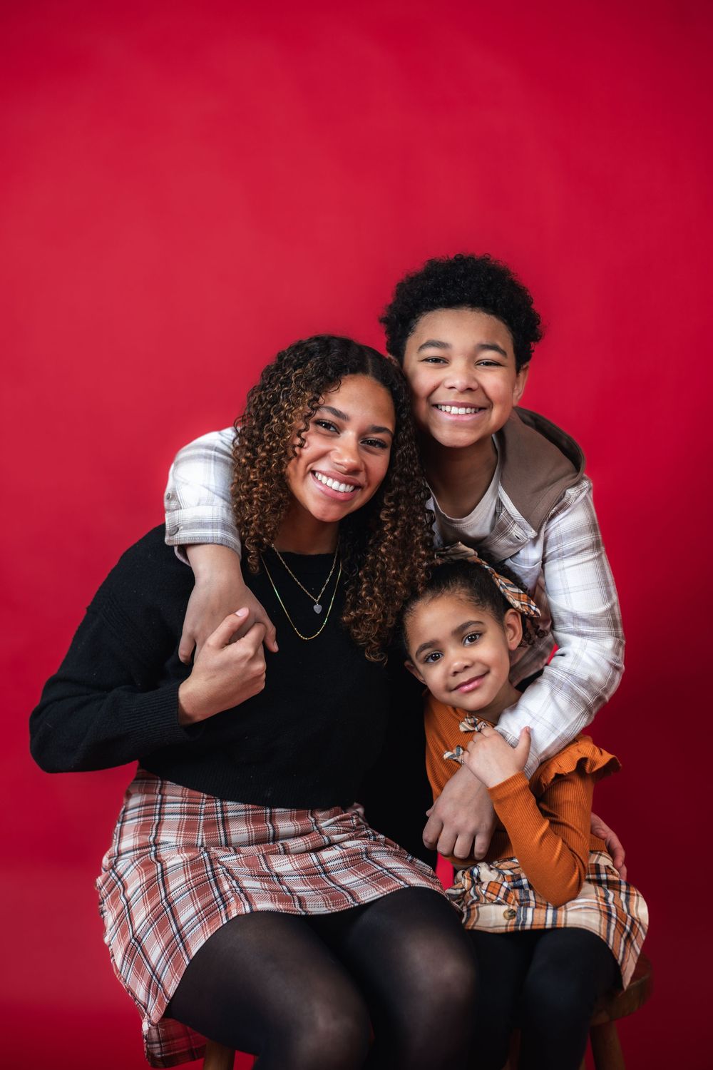 Two people share joyful embraces and laughter against a vibrant red background in a series of candid moments.