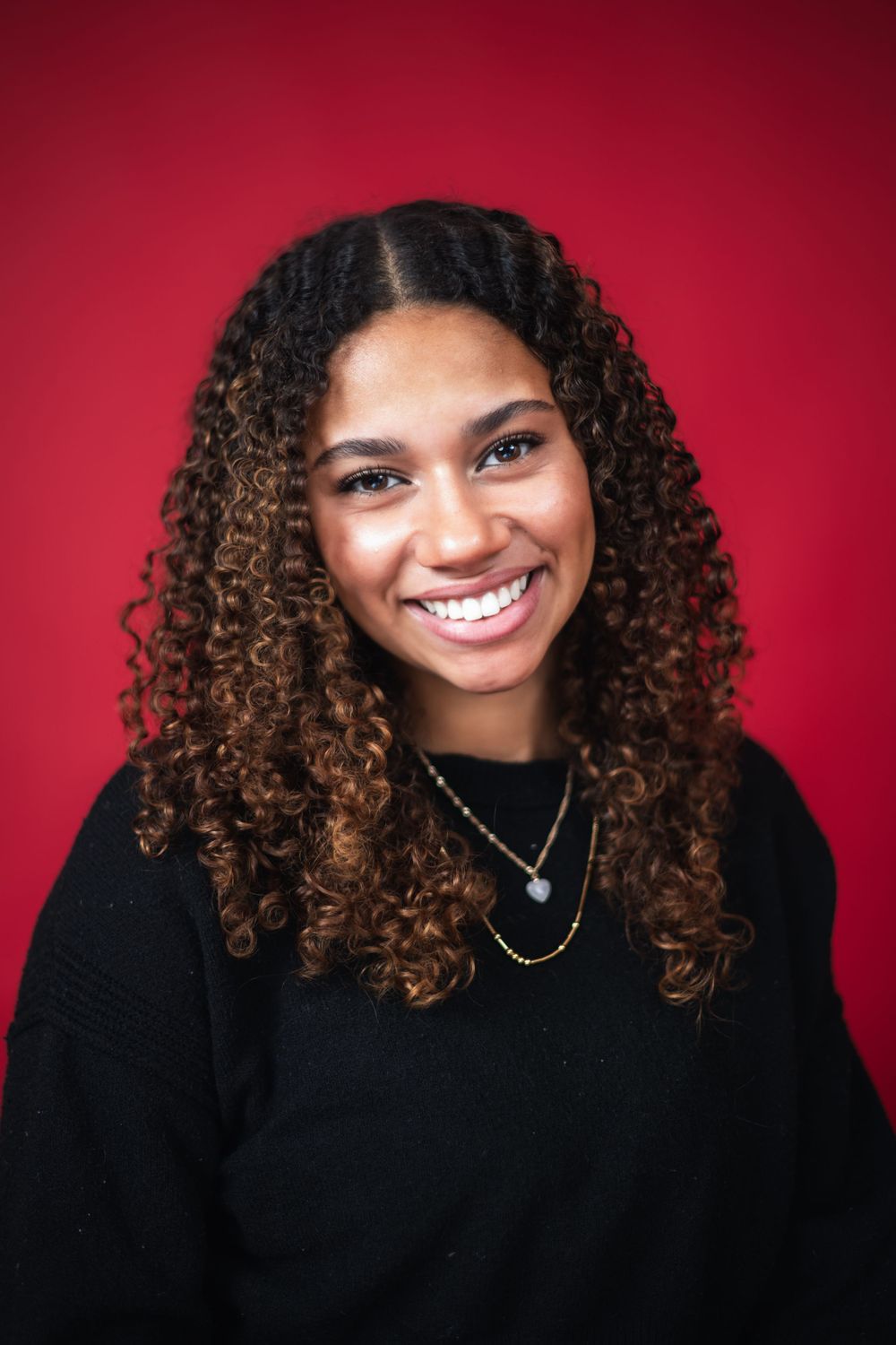 A series of five portrait photos showing curly hair and bright smiles against a deep red background.
