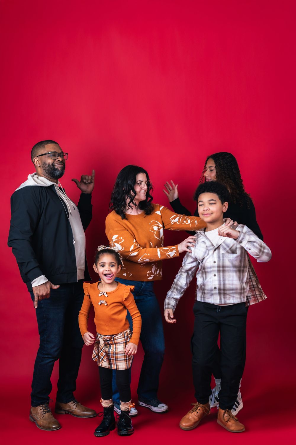 A playful sequence of poses against a red backdrop shows people interacting with an orange sofa in creative ways.