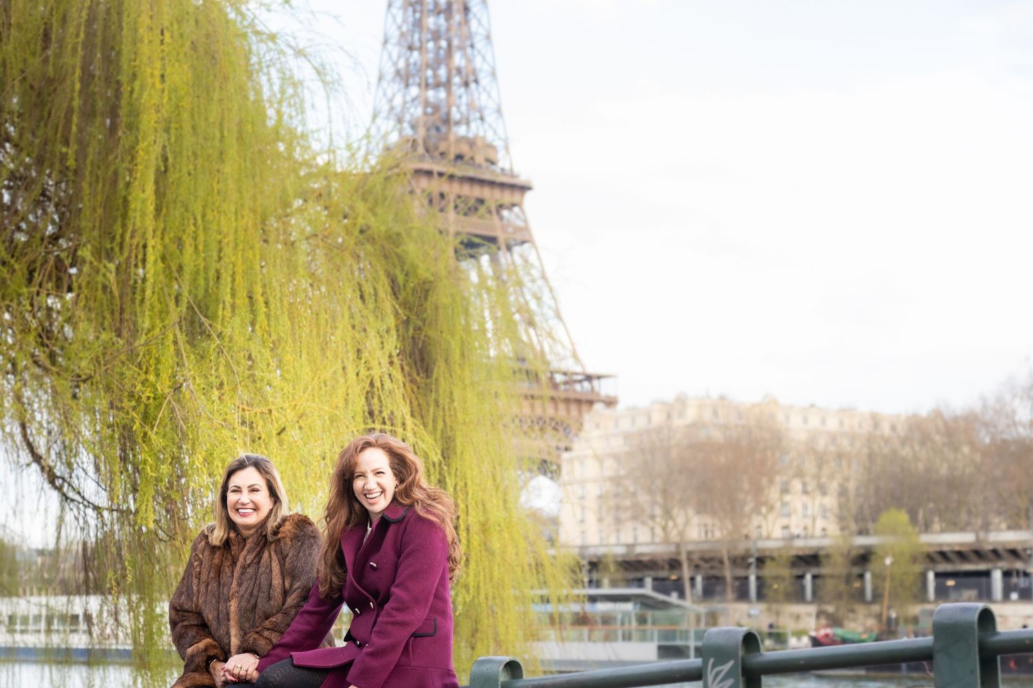 Two people embrace and smile warmly while wearing winter coats outdoors on a cold day.