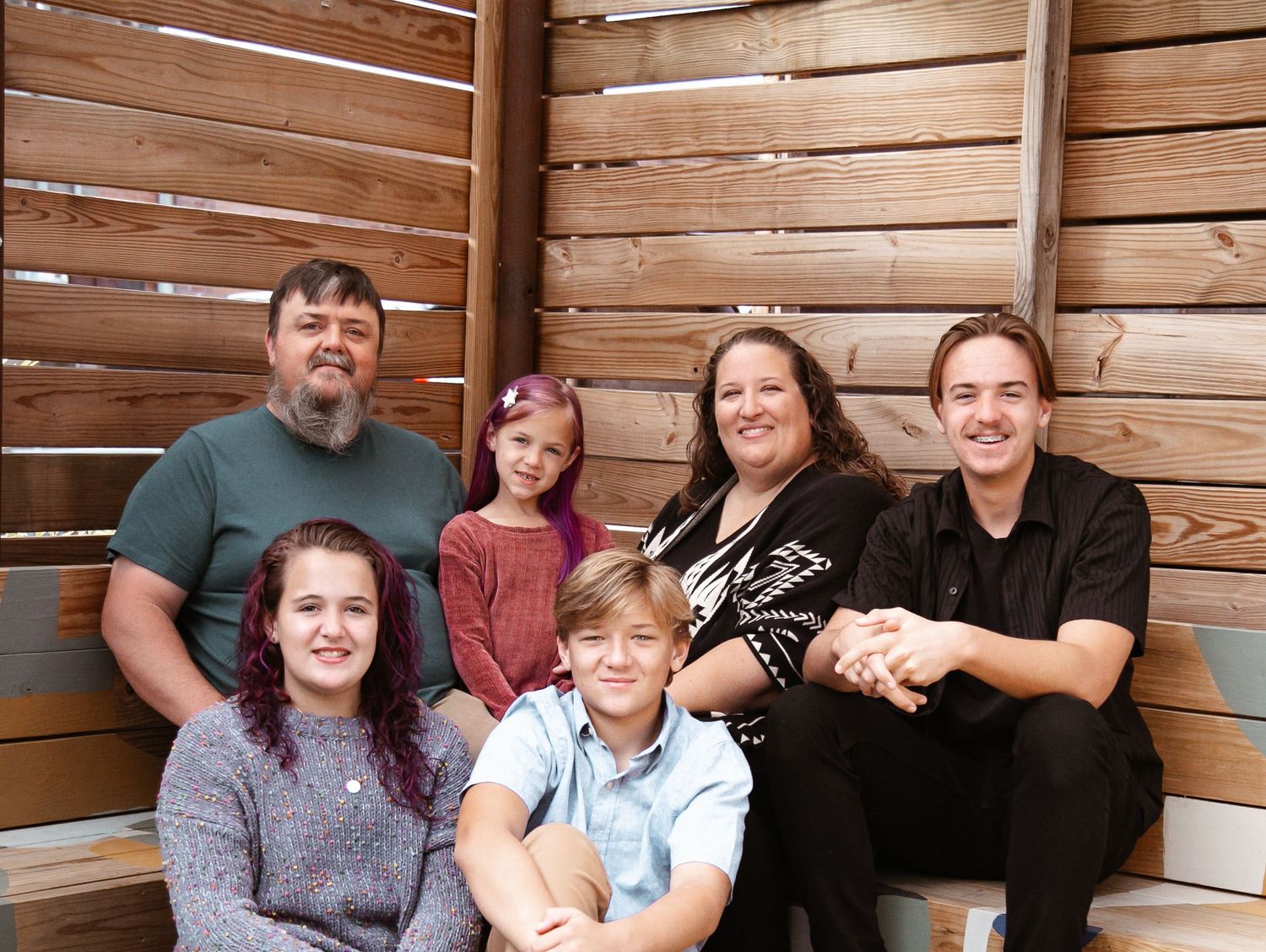 Family gathering scene with wooden paneled walls in the background.