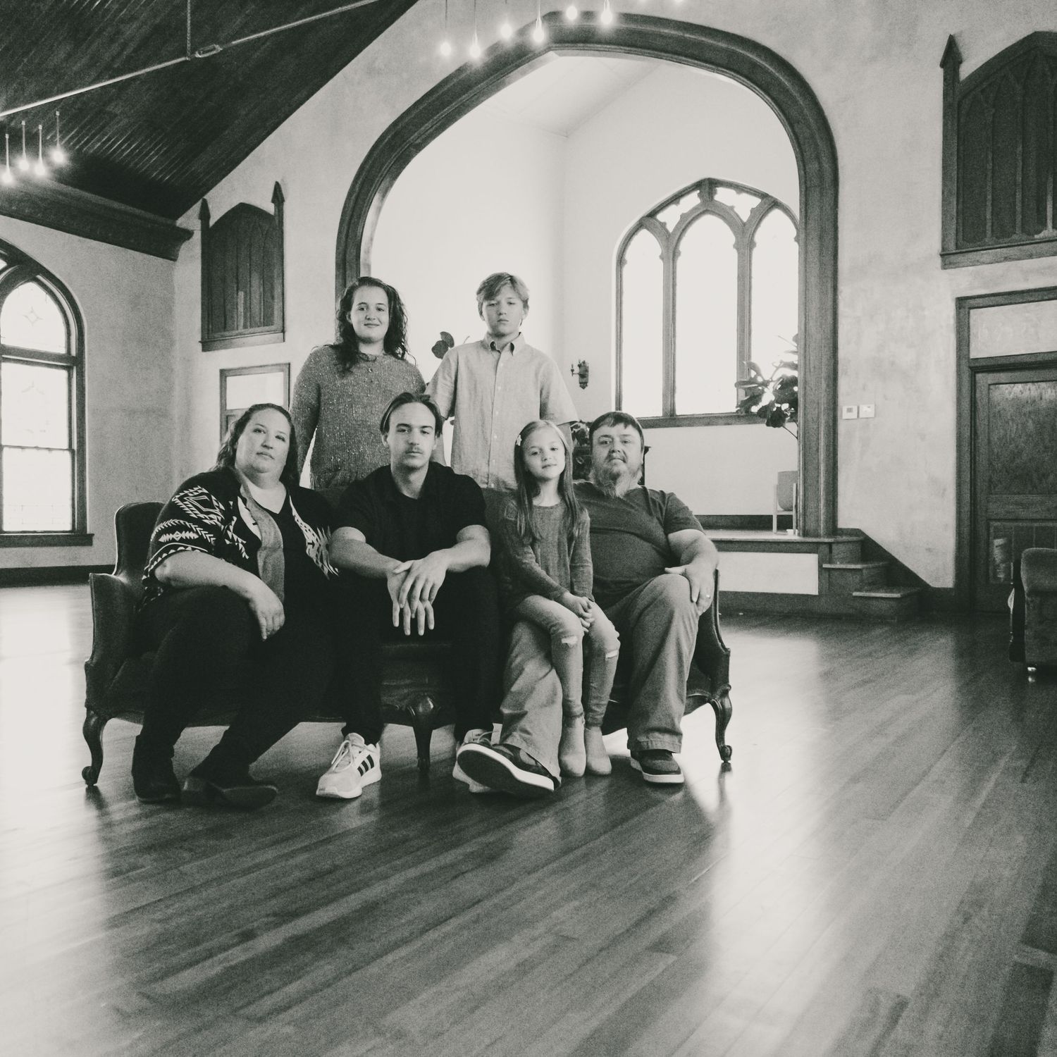 Group photo session in a historic building with hardwood floors and arched windows.