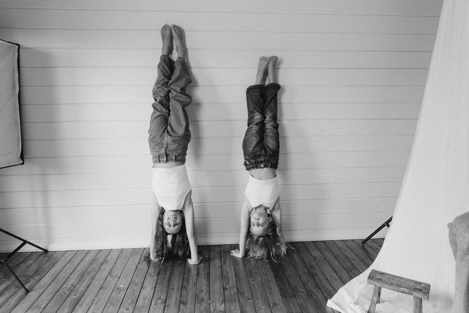 Two children do handstands against a white wall in a black and white photo in New Zealand.