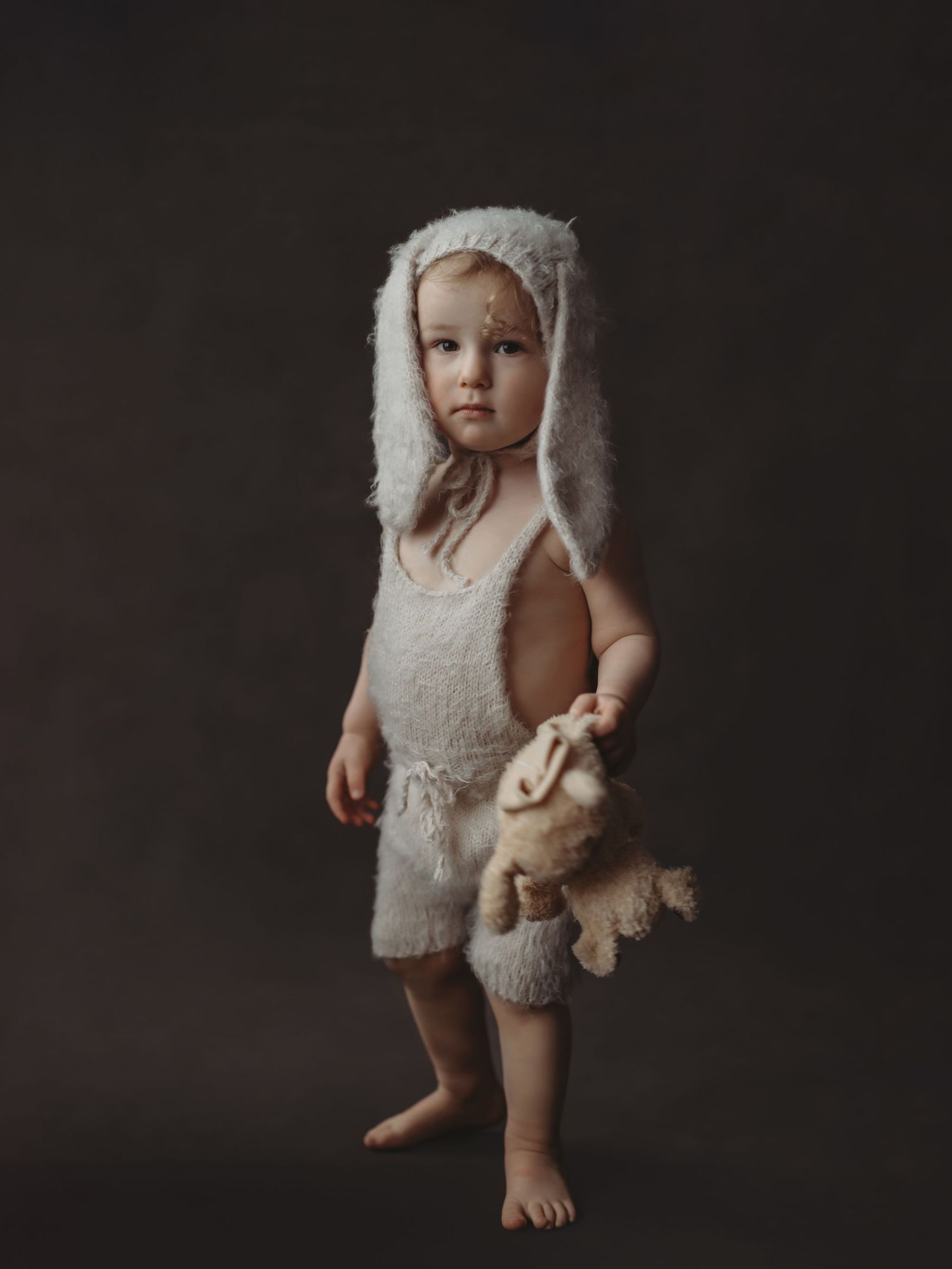 A series of connected photos showing a small child wearing a cozy white furry outfit against a dark background.