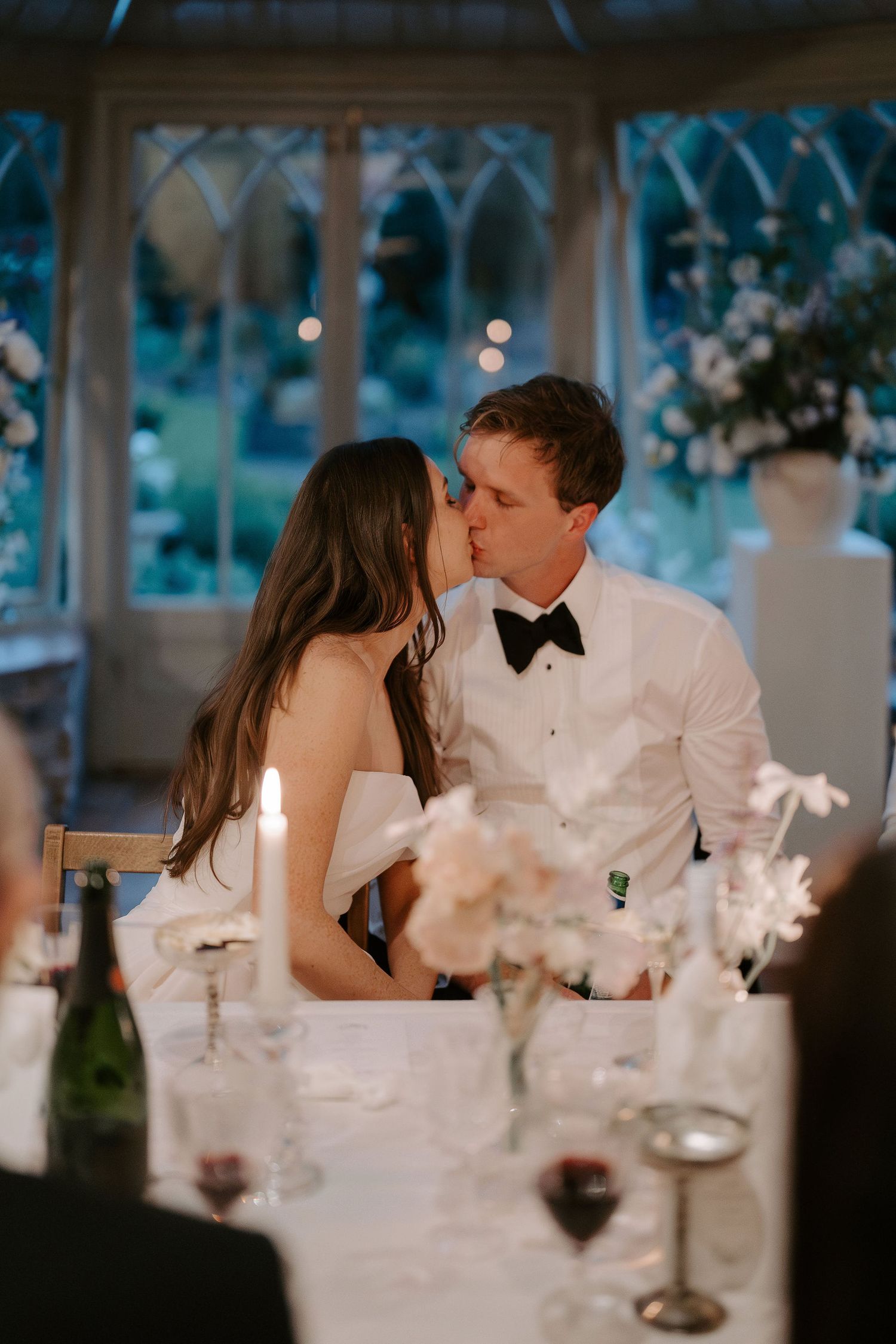 bride and groom sat sharing a kiss during their meal at dewsall court in herefordshire
