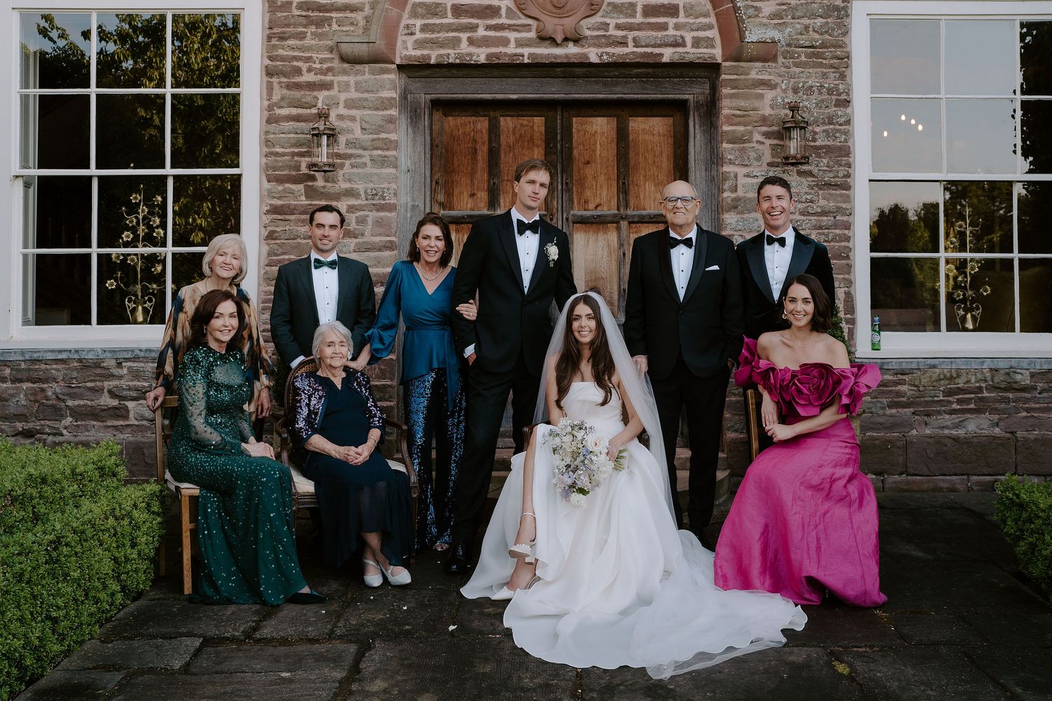 bride and groom portrait with family outside dewsall court in herefordshire