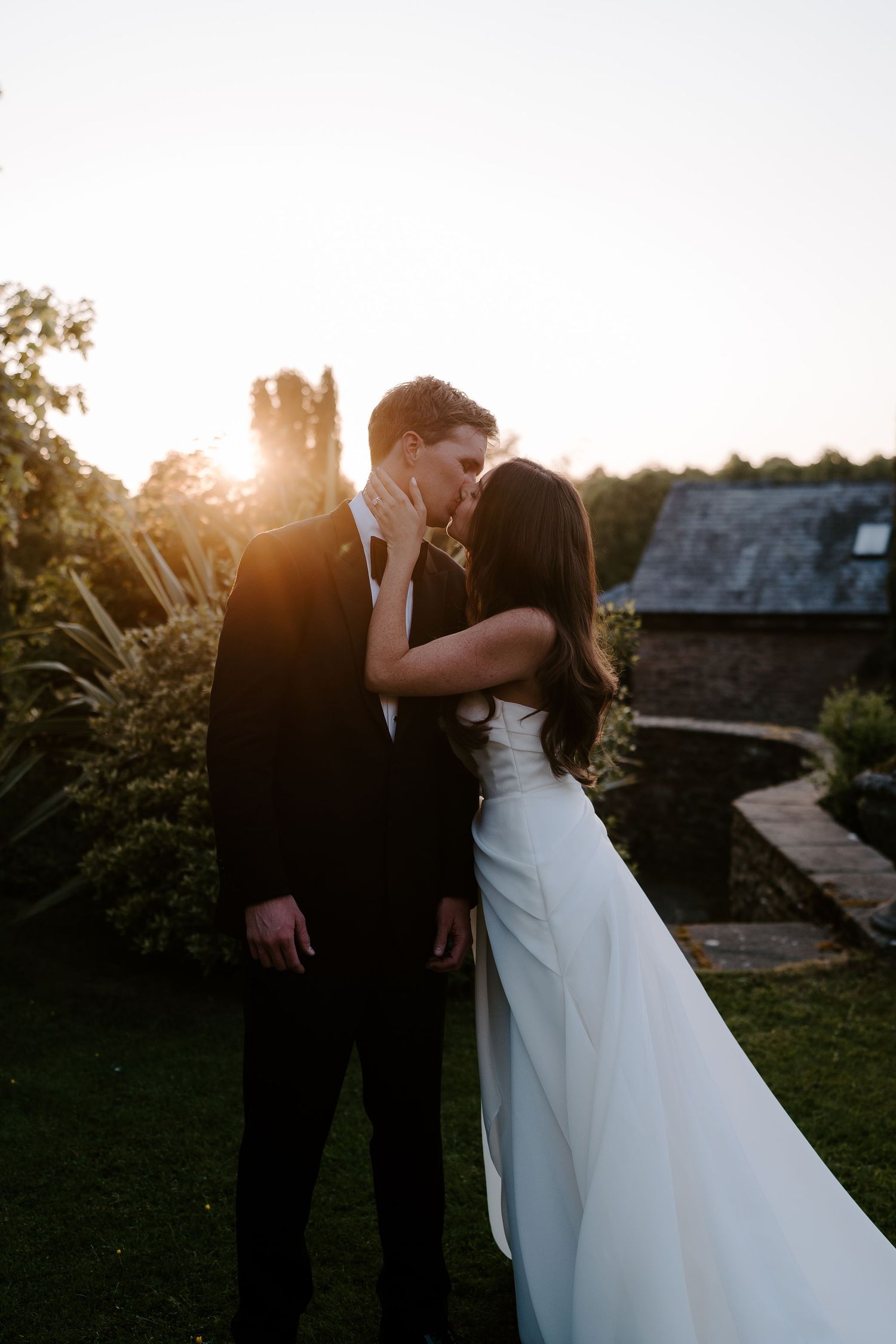 bride pulling groom in for a kiss in the setting sun at dewsall court in herefordshire