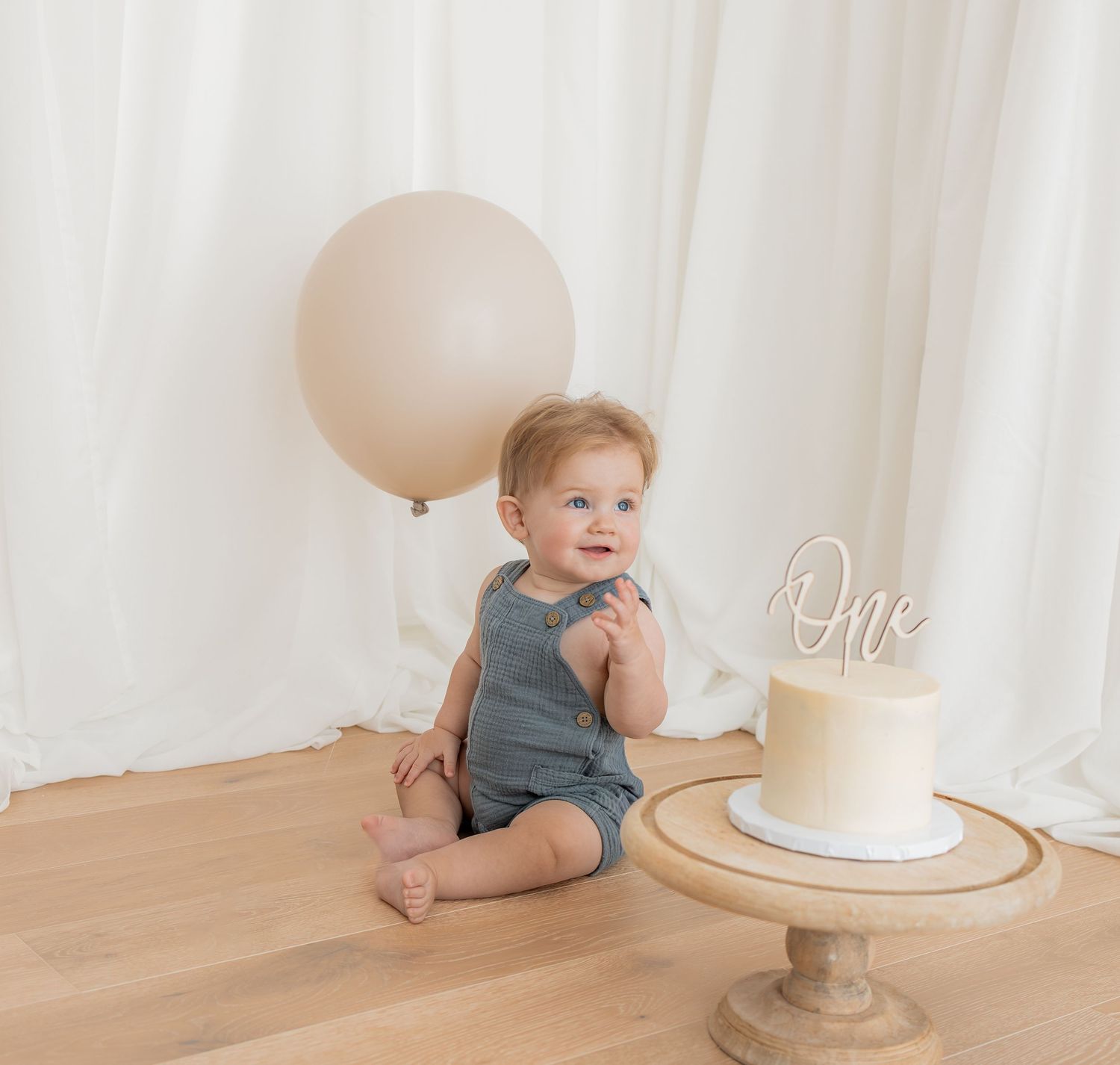 Baby messily eating birthday cake during first birthday photoshoot. Photography in Buckinghamshire.