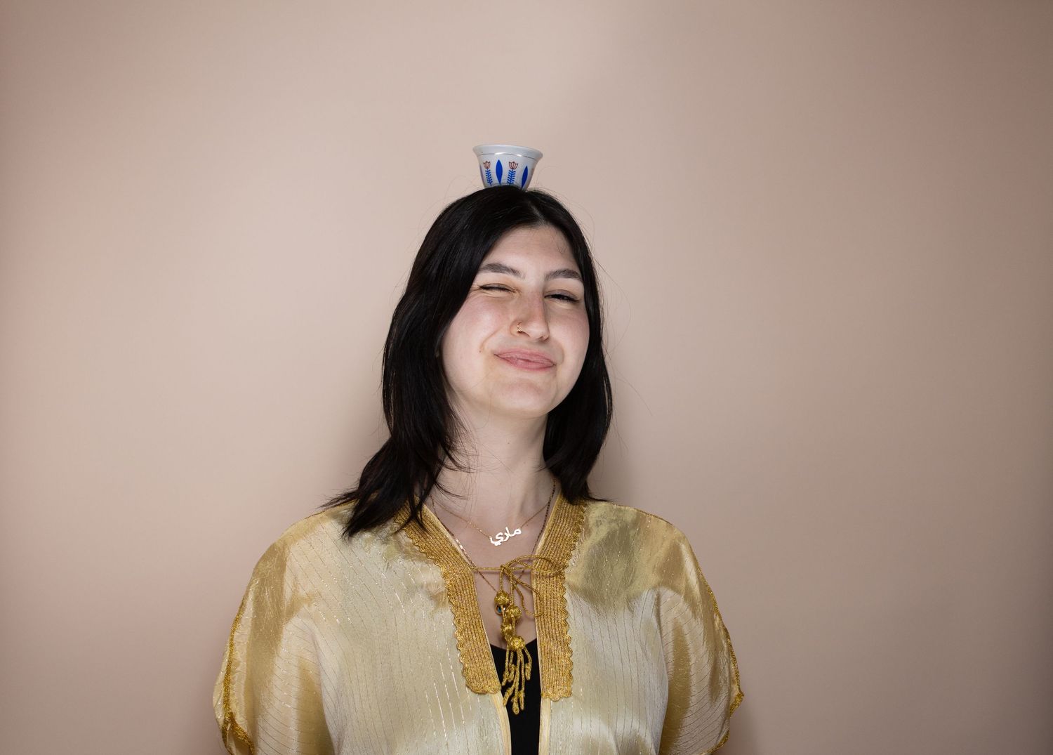 A person in a golden silk blouse poses against a neutral beige background in a photo series.