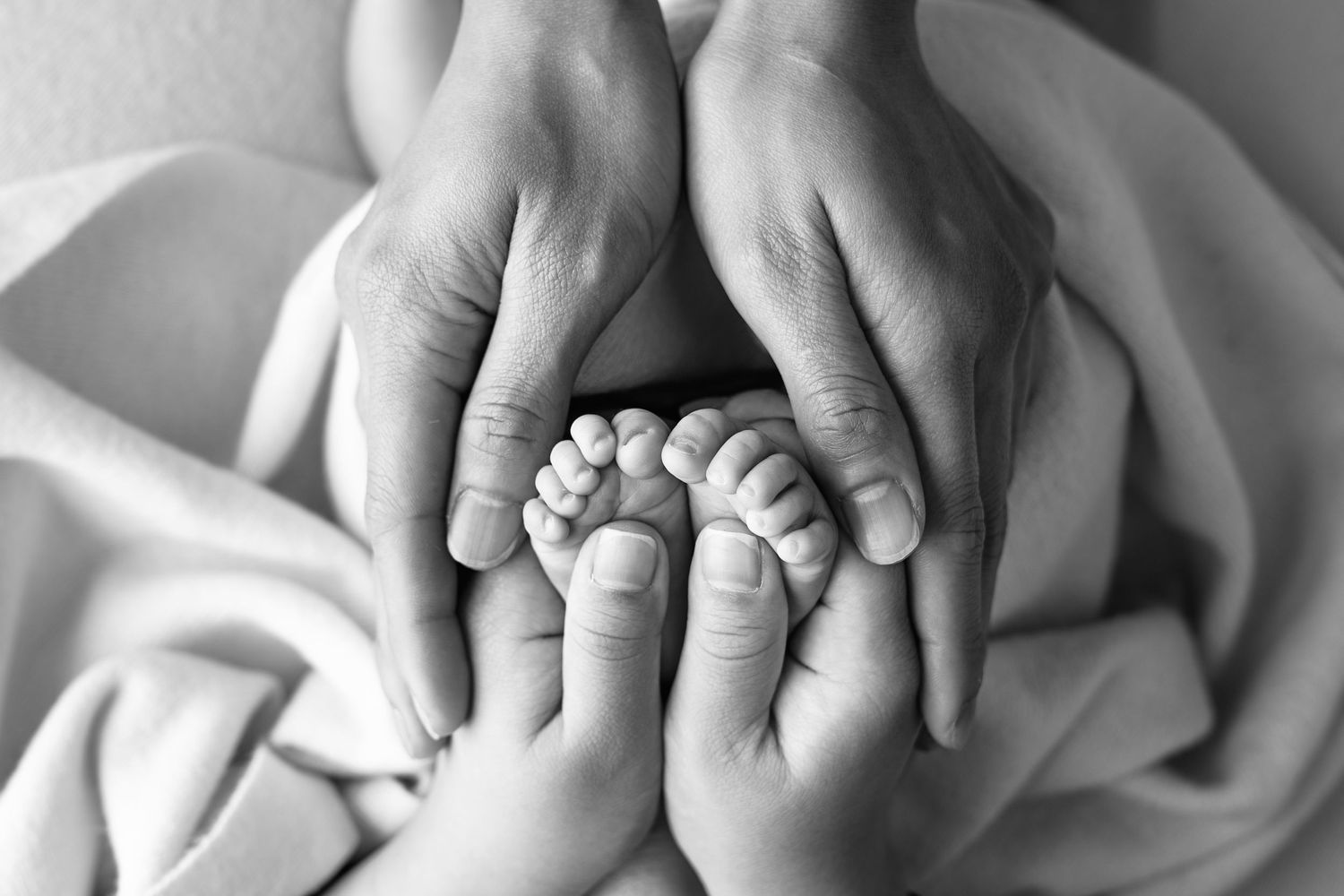 Black and white close-up of gentle holding hands showing tender connection.