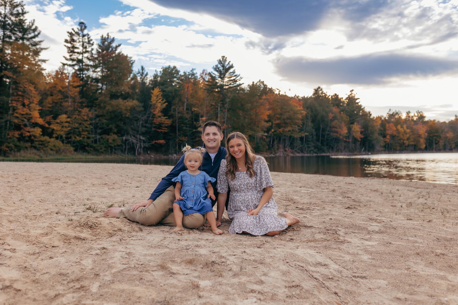 Sweet family of three sitting on the beach during their family photography session in Rhinelander, Wisconsin