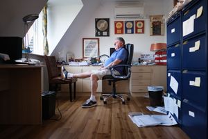Person relaxing in a modern office chair with blue cabinets and wooden flooring in the background.