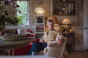 A cozy living room scene with someone relaxing in an armchair, surrounded by vintage decor and warm lighting.