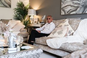 Luxurious living room setting with plush white bedding, decorative pillows, and tropical plants creating a cozy atmosphere.