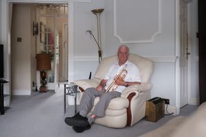 A person relaxes in a cream-colored armchair while reading in a bright, minimalist living room.