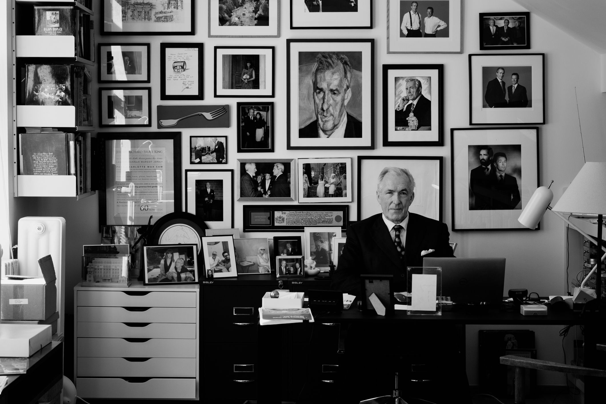 A wall gallery of black and white portrait photographs arranged in a grid pattern against a white background.