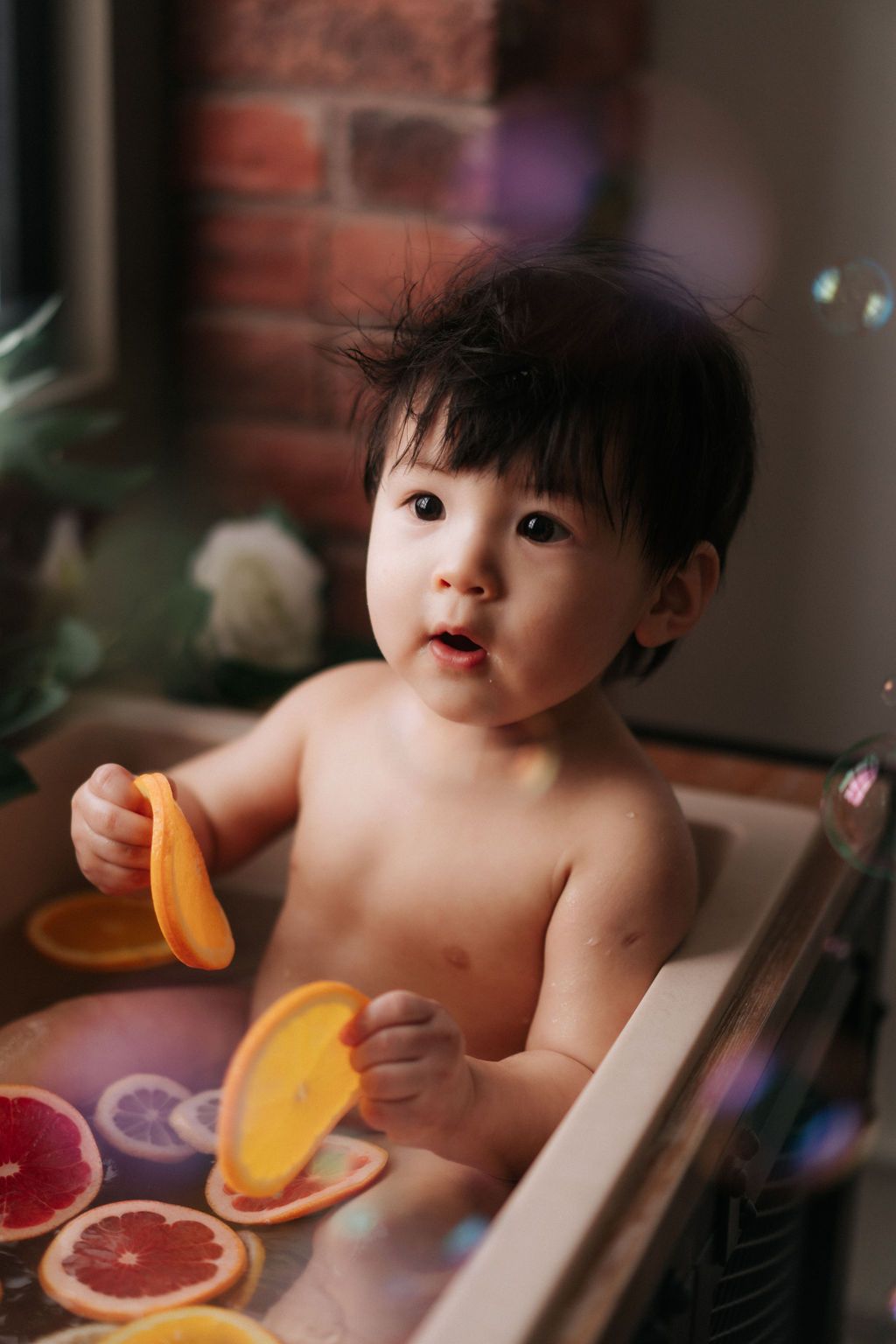 Cake smash photo session setup with white balloons, sunflowers and a baby enjoying their first birthday celebration.
