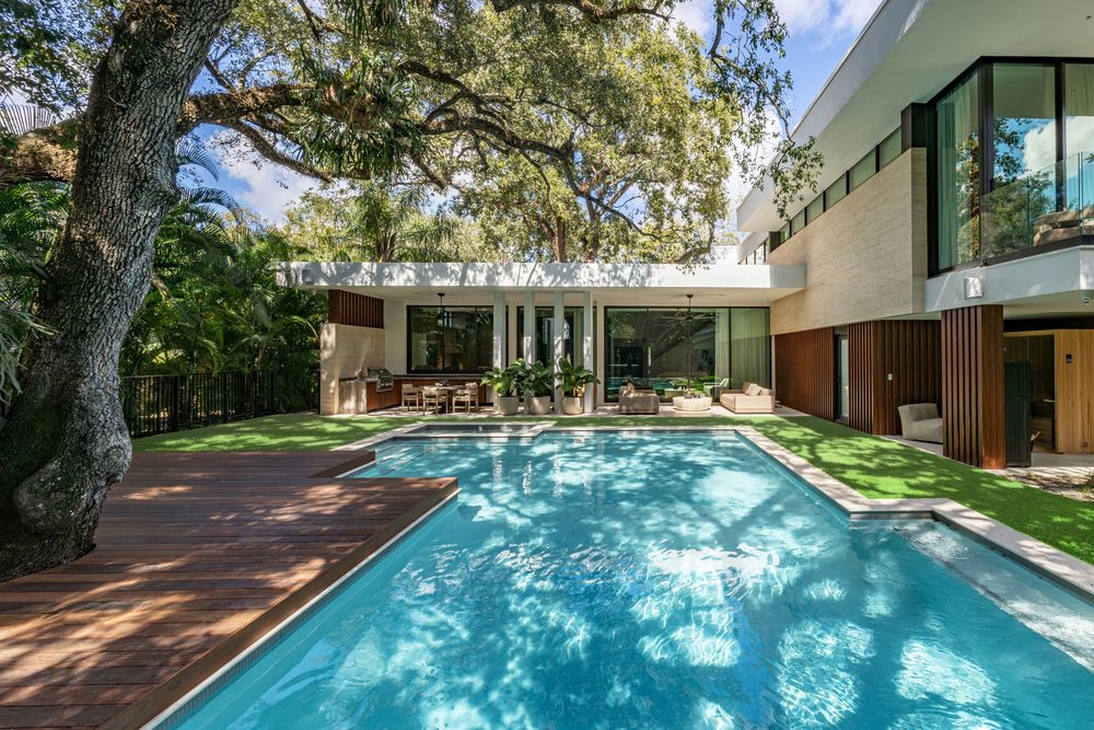 Elegant swimming pool with water features surrounded by lush trees and modern architecture.