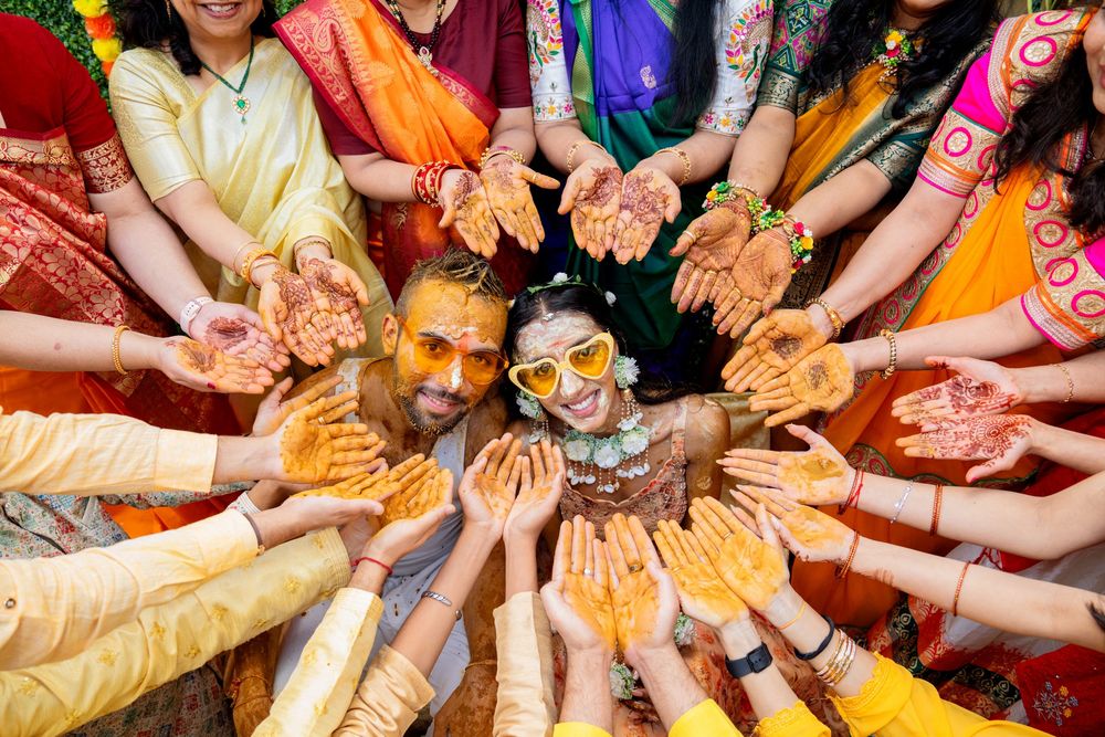 Hands covered in vibrant yellow and orange Holi powder form a circle during traditional Indian festival celebrations.