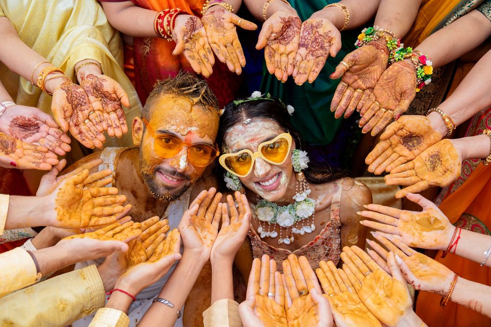 Hands covered in orange and yellow Holi powder shown in a circular formation during festival celebrations.