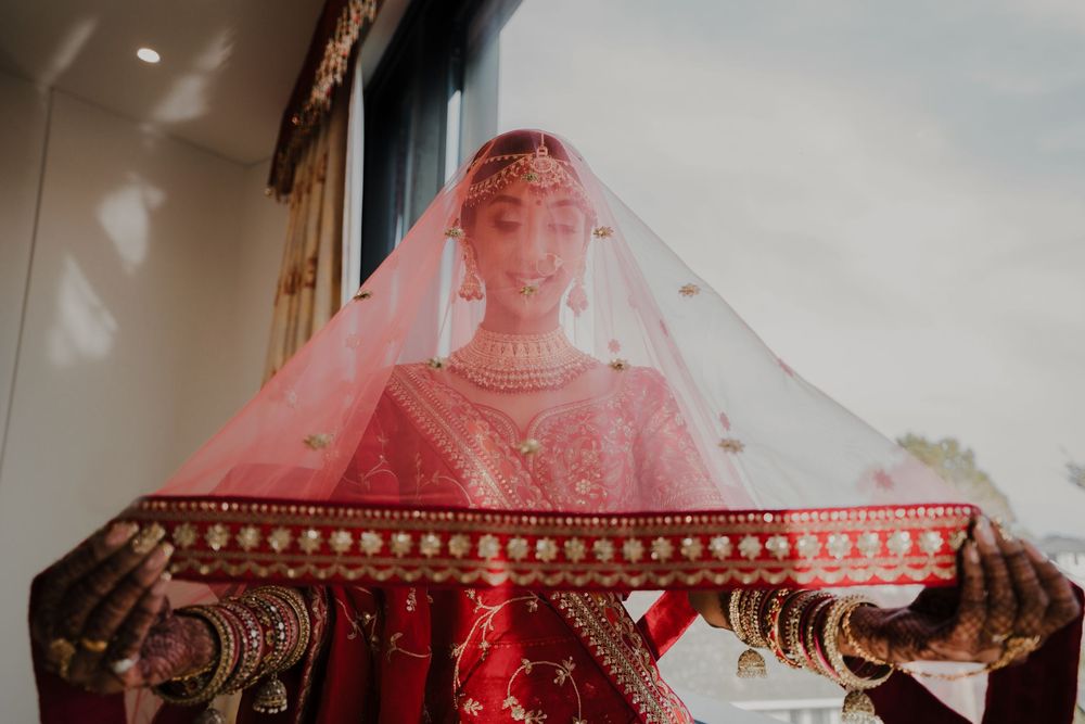 A traditional Indian bridal scene with intricate henna designs and flowing red wedding attire during a ceremony.