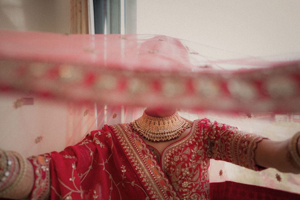 A series of elegant red and gold Indian wedding lehengas and bridal outfits displayed in a row.