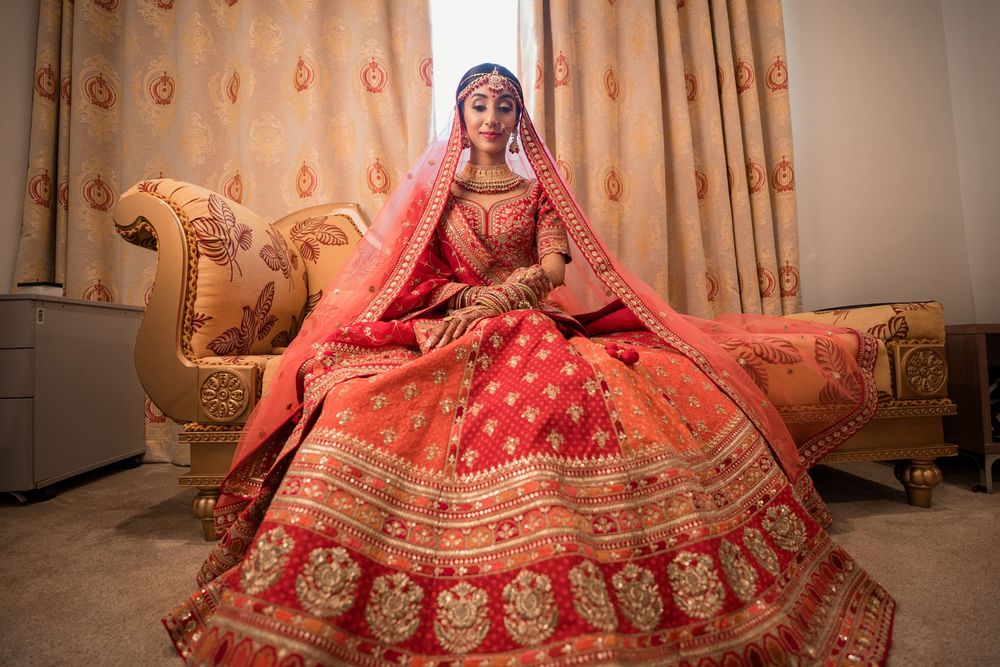 Traditional Indian bridal attire featuring an ornate red and gold lehenga on a luxurious gold chaise lounge.