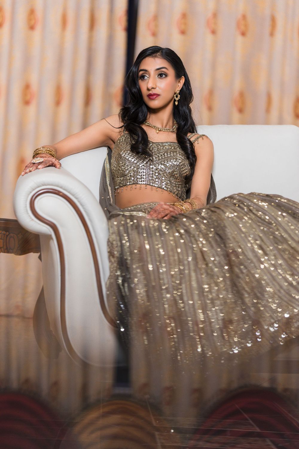 A glamorous evening gown with sparkling sequins drapes elegantly across an antique style lounge chair.
