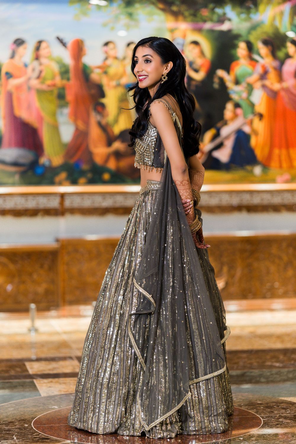 Woman in sparkly silver and black gown twirls gracefully in outdoor setting during festive celebration.
