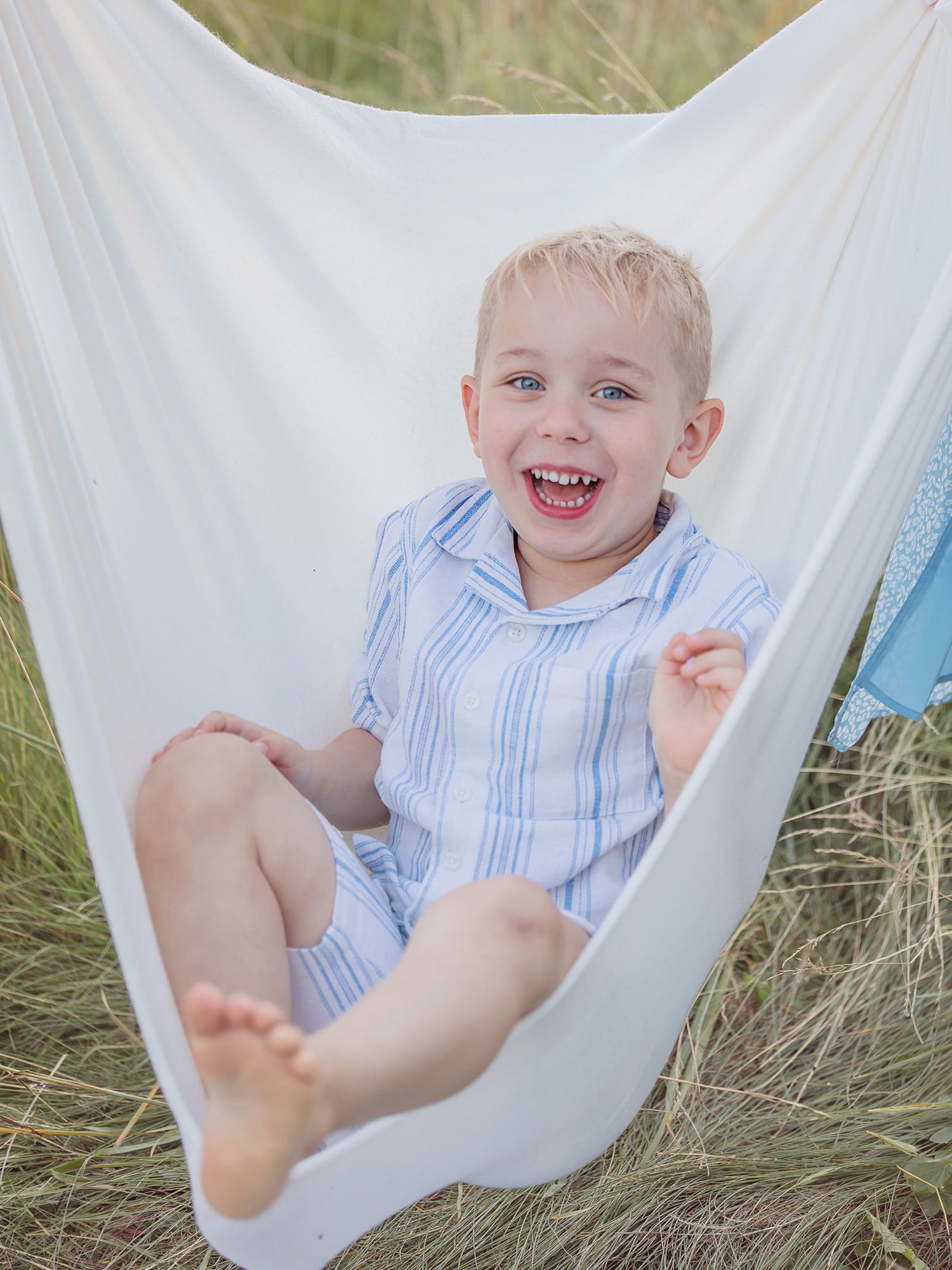 Barn skrattar och gungar på vit filt, familjefotografering i Västerås, Memoriesbym