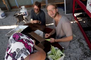 People working together at a table in a workshop setting with equipment visible.