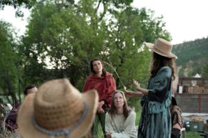 A group enjoying an outdoor social gathering with various clothing styles and hats.