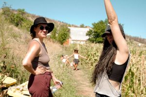 A group enjoying a sunny day on a dirt path surrounded by tall vegetation and hills.