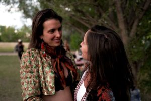 Two people in floral and patterned clothing having an intimate conversation outdoors at dusk.