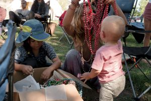People sitting in camping chairs with colorful beads and accessories at an outdoor event.