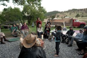 A casual outdoor meetup with attendees sitting on chairs and gravel ground.