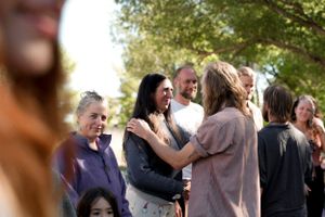 Cheerful group of people socializing outdoors under green trees.