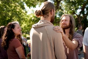 Friends greeting each other warmly at an outdoor social event.