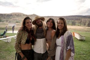 Friends pose together at an outdoor gathering with desert mountains in the background.