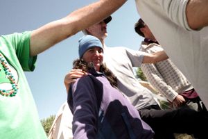 A crowd lifts someone up during an outdoor gathering in sunny weather.