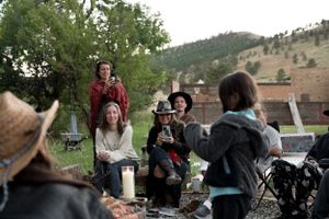 An outdoor social gathering with people sitting in chairs around a central point.