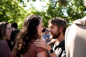 Two people sharing an emotional embrace at an outdoor social gathering.