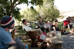 Group gathered outdoors under trees for a casual social gathering with musical instruments.