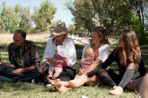 Group relaxing on grass at outdoor social gathering.