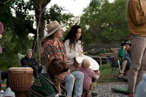 People gathered outdoors with musical instruments including a drum during a casual meetup.