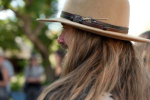 Close-up of long hair under a brown leather hat with decorative band.