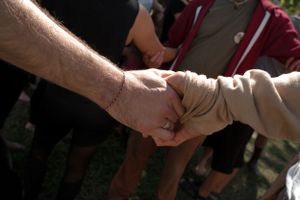 Close-up shot of hands clasped together during a gathering.