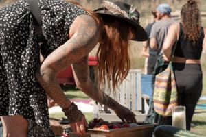 Person in floral dress setting up items at an outdoor market or event.