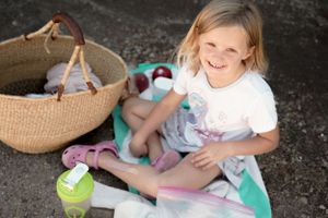 A young child sitting on the ground with a basket and toys nearby.