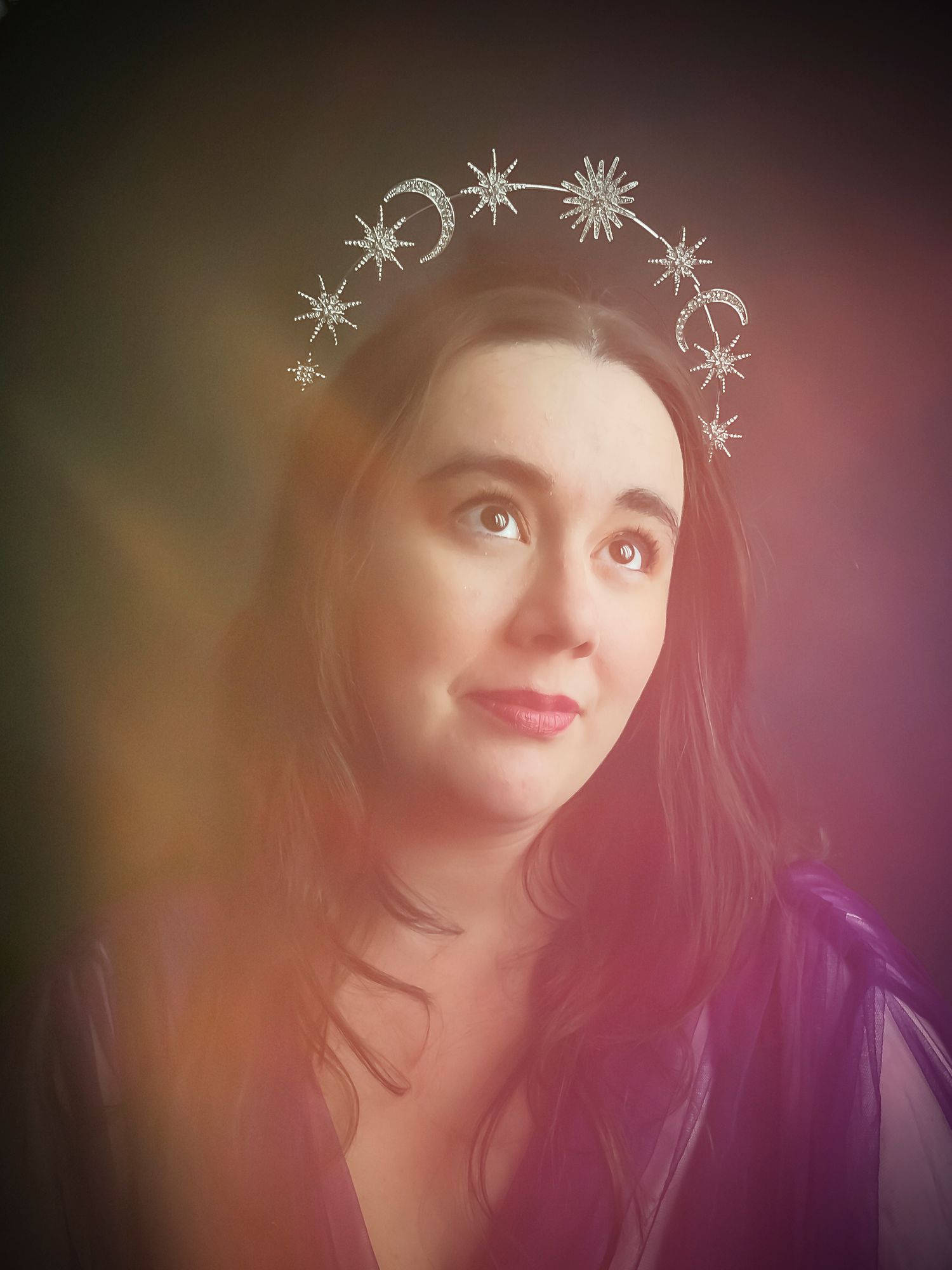 Portrait with decorative celestial elements including moons and stars floating overhead in a dreamy soft-focused style.